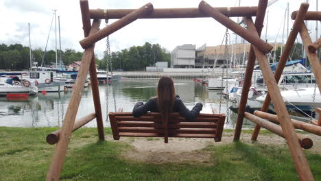 hermosa foto de una mujer balanceándose y al fondo se puede ver un muelle deportivo