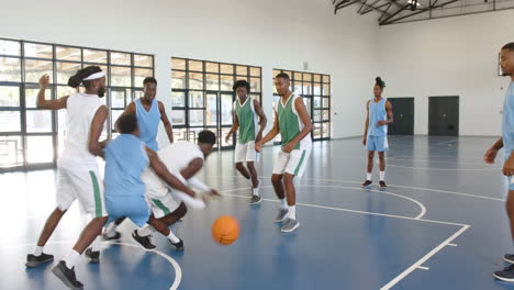 multiracial male basketball players playing basketball, one player fouling in gym