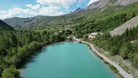 people hiking along turquoise light blue glacial lake in la grave - la meije, french alps - aerial dolly forward