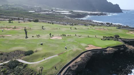 Aerial-pullback-of-stunning-golf-course-overlooking-sweeping-blue-ocean-views-at-midday