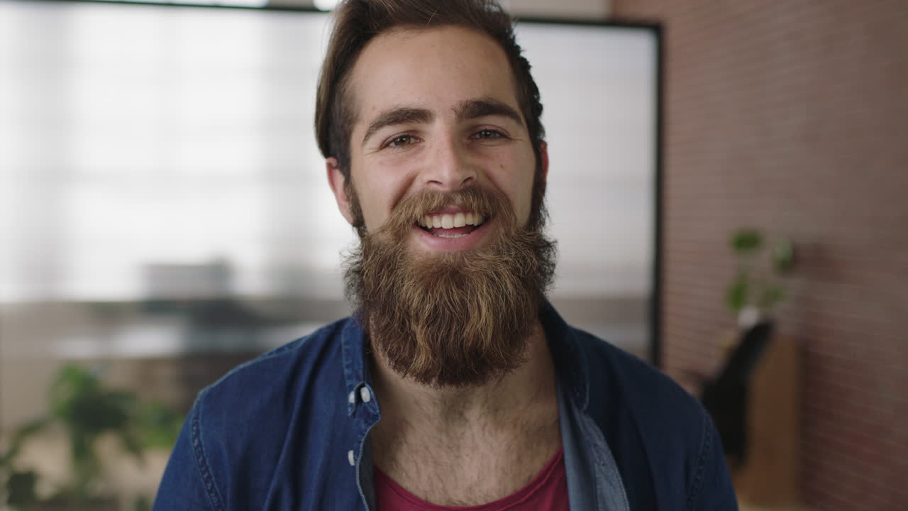 close up portrait of attractive young hipster man with beard smiling happy enjoying successful start up company cute male in office workspace
