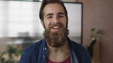 close-up-portrait-of-attractive-young-hipster-man-with-beard-smiling-happy-enjoying-successful-start-up-company-cute-male-in-office-workspace