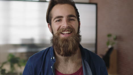 retrato en primer plano de un atractivo joven hipster con barba sonriendo feliz disfrutando de un exitoso inicio de empresa hombre lindo en el espacio de trabajo de la oficina