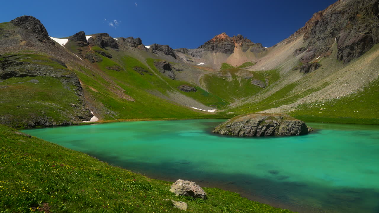 공중 영화 드론 얼음 호수 유역 실버턴 섬 호수 여름 수영 푸른 은 물 알파인 드라 놀라운 산맥 눈 야생 꽃 낮에 아름다운 느린 왼쪽으로
