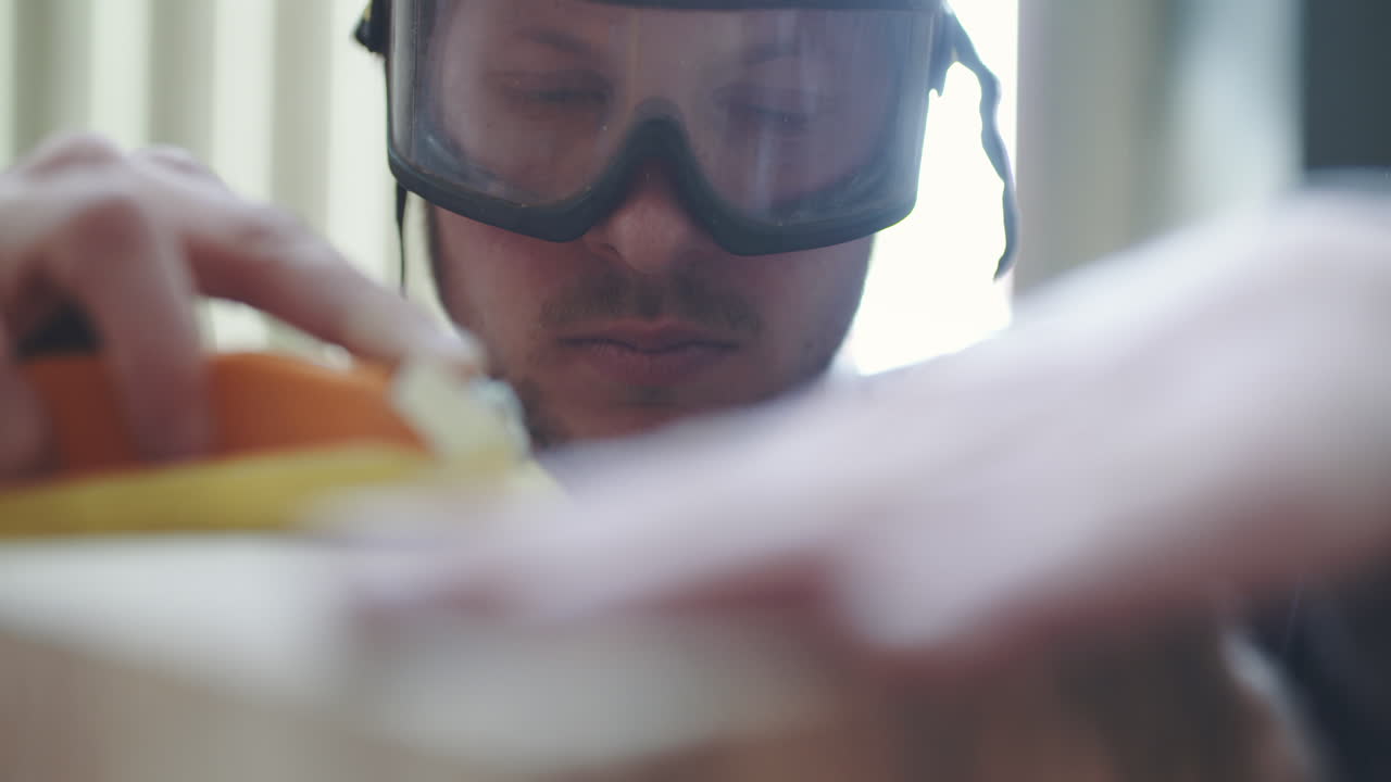 Man Sanding Wood with Safety Goggles in Workshop