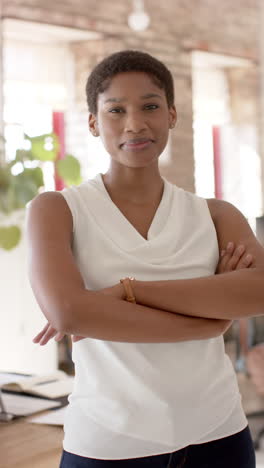 vertical video of portrait of happy african american casual businesswoman in office in slow motion