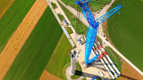 wind turbine under construction with large crane at daytime in austria - drone shot