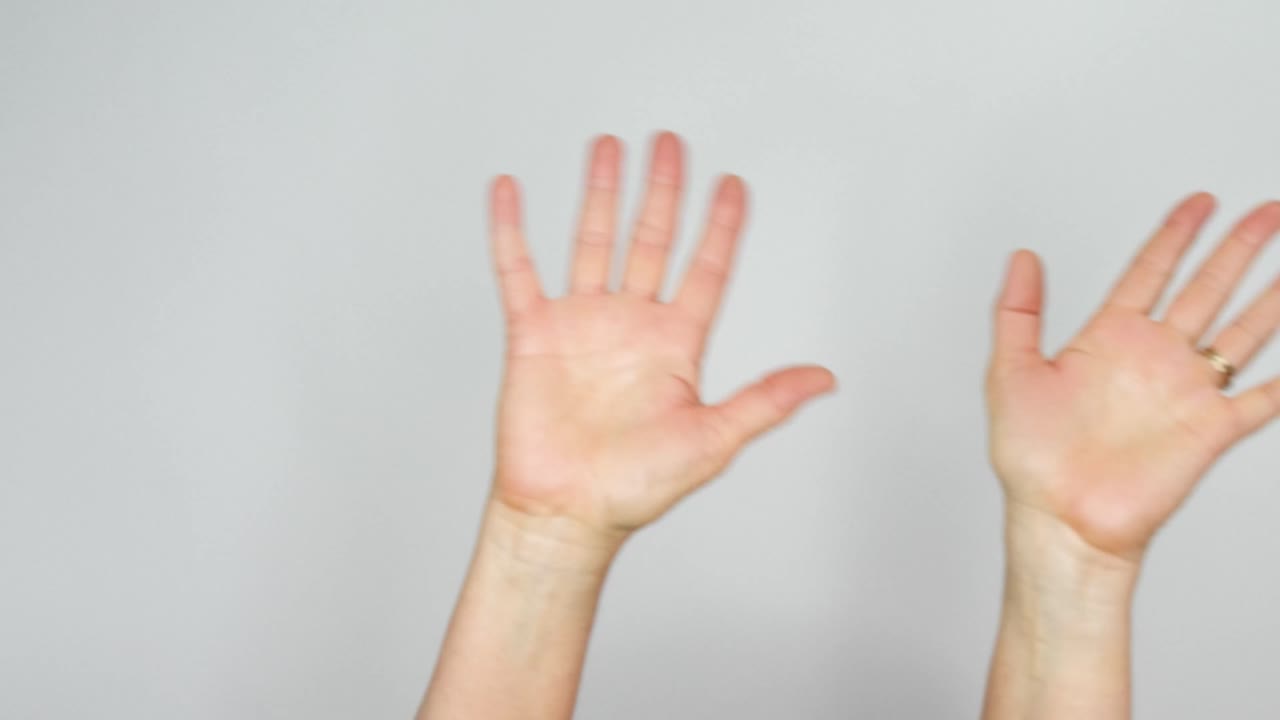 두 개의 손바닥이 흰색 배경 앞에서 인사를 하며 흔들립니다.
