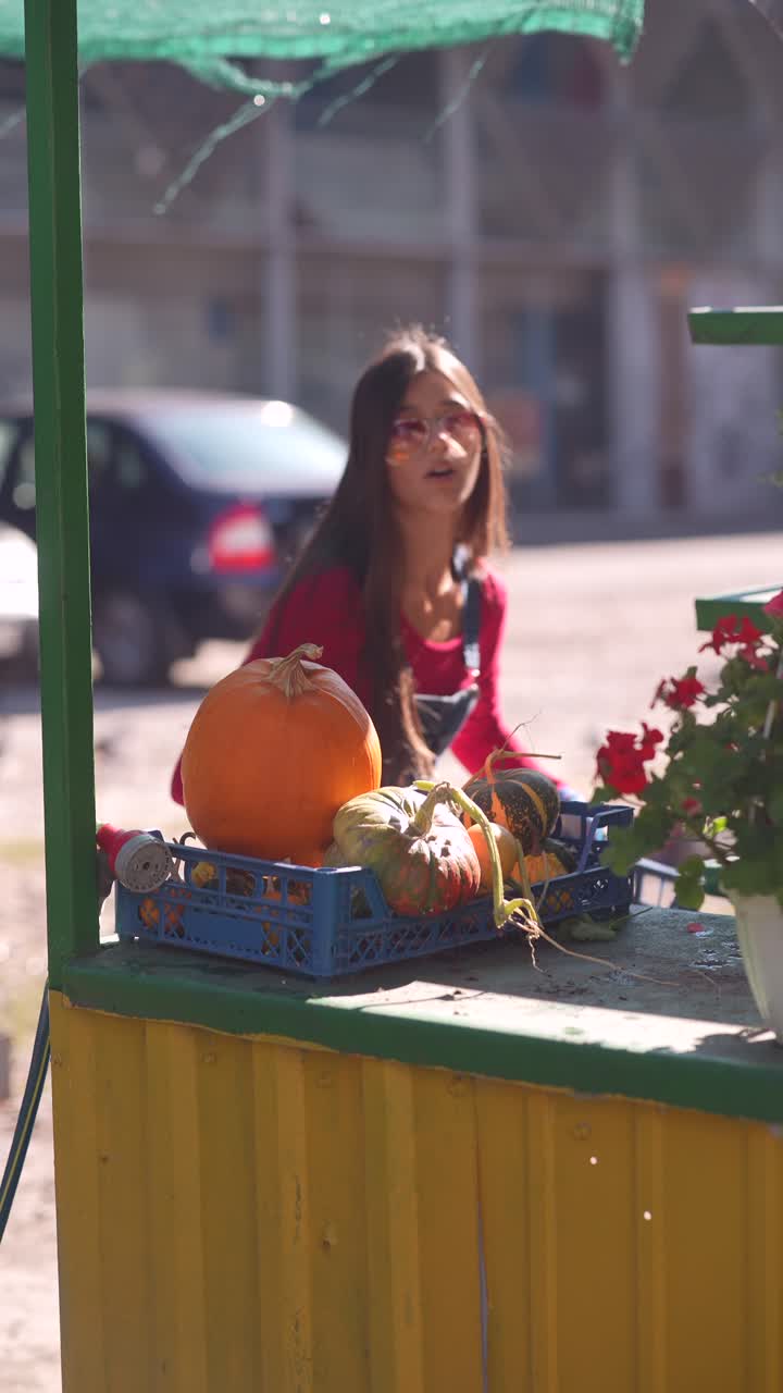 mujer vendiendo calabazas y calabazas en un mercado al aire libre