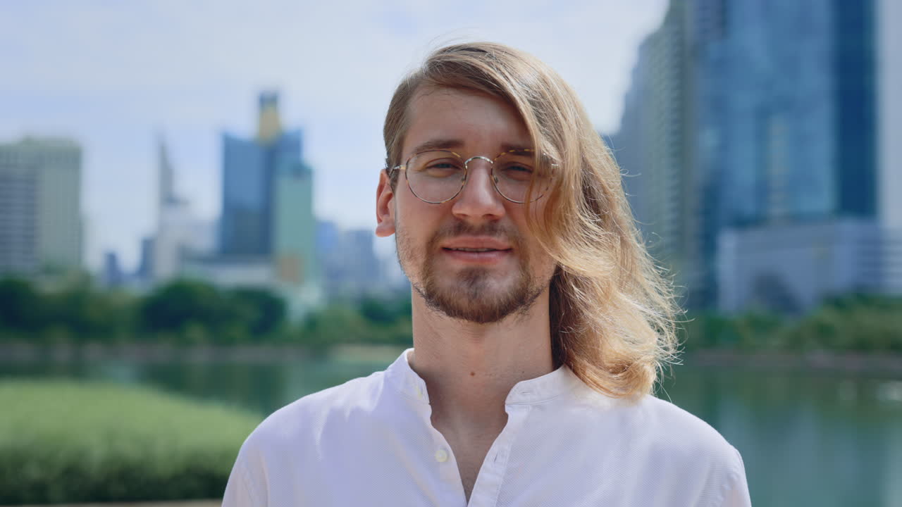 Smiling Man with Long Hair in City Park