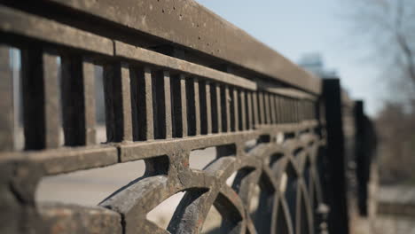 close-up view of a weathered metal fence bridge with cars passing with speed on the bridge