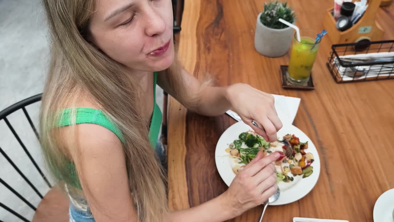 mujer comiendo ensalada en un restaurante