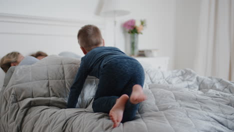 Niños-Felices-Saltando-En-La-Cama-Despertando-A-Madre-Y-Padre-Disfrutando-De-Una-Mañana-Juguetona-Con-Niños-El-Fin-De-Semana-Por-La-Mañana-En-Casa-Imágenes-De-4k