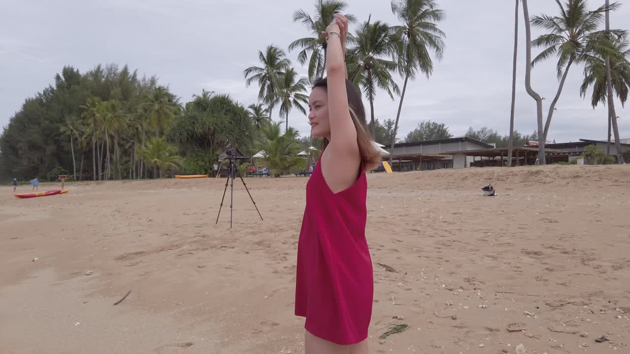 joven asiática usa vestido rojo y camina relajándose en la playa en vacaciones de verano en cámara lenta