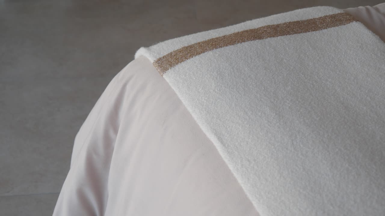 белое полотенце, сложенное на постели.