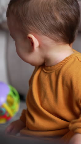 caucasian child playing with toys indoors. cute kid pushes the ball and watches it rolling. close up. vertical video