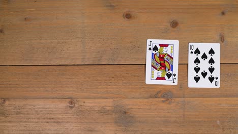 a person laying out a spades royal flush on a wooden table to educate the viewer on how to play poker