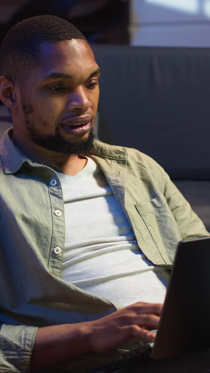 Vertical Video African american casual man solving daily tasks on his laptop at home
