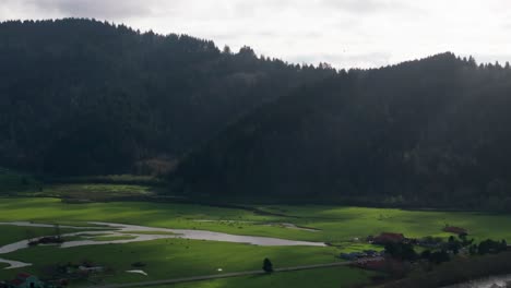 Static-drone-shot-of-the-sunrays-hitting-a-green-pasture-in-California