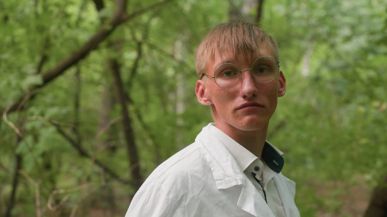 Side view of scientific researcher standing in forest adjusting white coat while looking focused, surrounded by lush greenery and natural light, emphasizing outdoor preparation, concentration