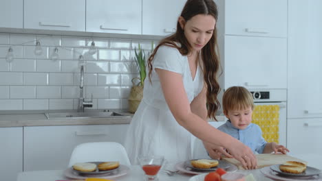 young mother helps a child to cook burgers in the kitchen