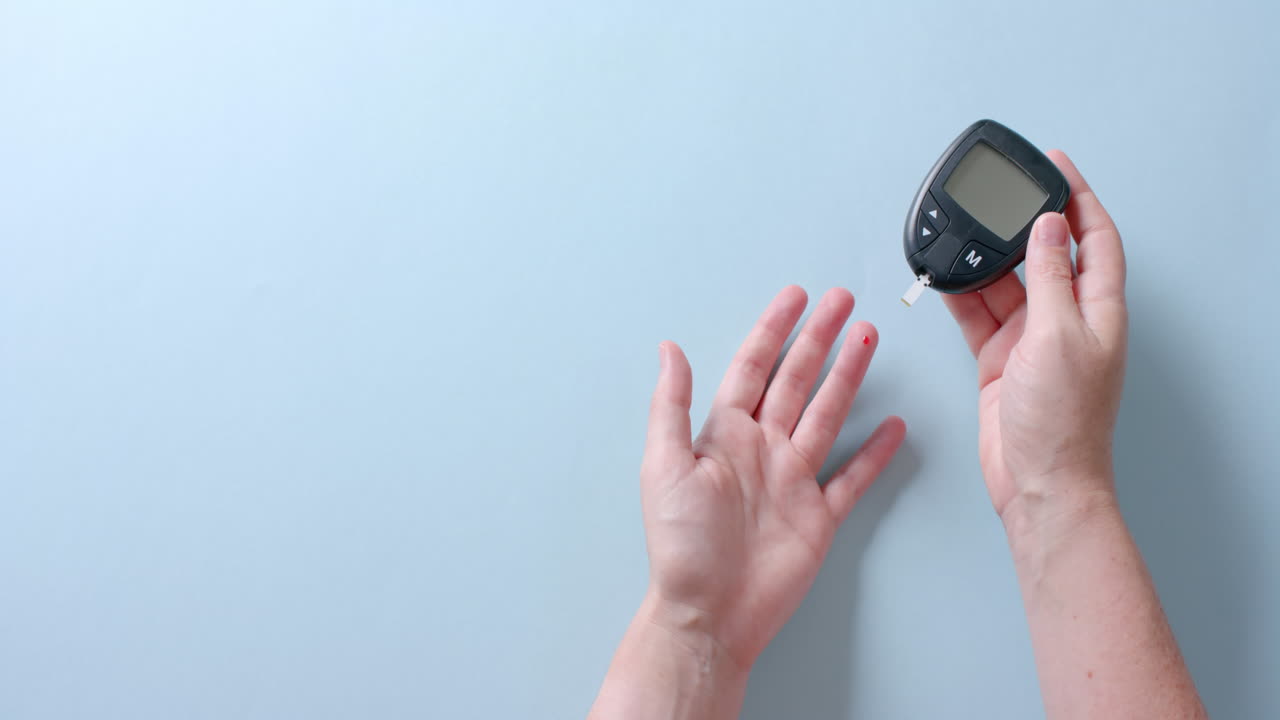 Hands of caucasian woman checking blood sugar level using glucometer, copy space, slow motion