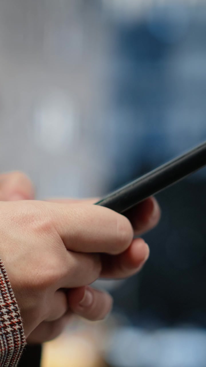 Vertikální video: Detail dotykové obrazovky chytrého telefonu používané podnikatelkou v centru města.