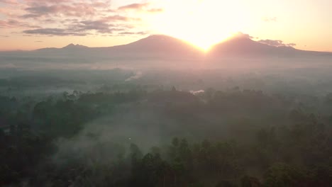 droneshot of famous borobudur temple with mountains and sunrise on the background - magelang,indonesia