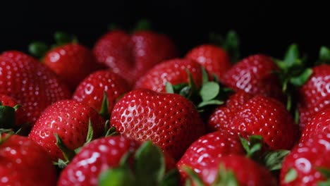 juicy strawberries with green leaves glistening against a dark backdrop, perfect for culinary visuals