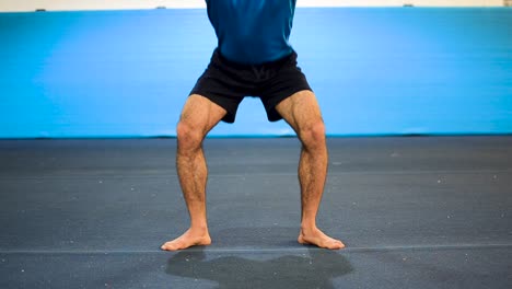 a still shot of a guy doing squats in a gymnastics gym