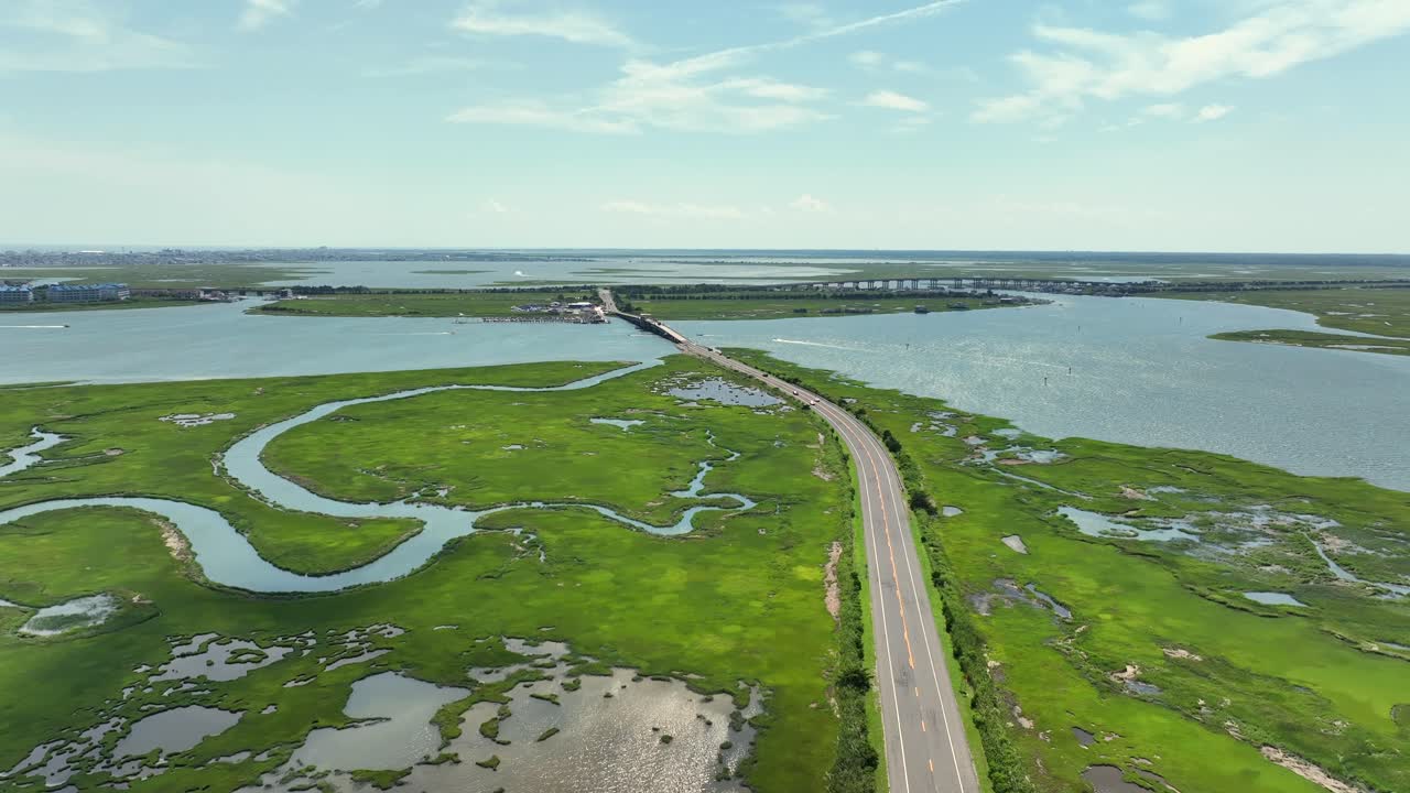 Flowing River delta in marshland and wetland of Wildwood, New Jersey. Sunny day in summer. Street and bridge connecting islands. Aerial landing shot