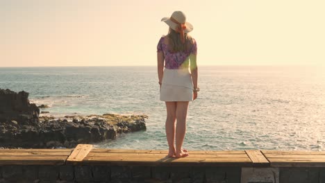 Mujer-Joven-Con-Ropa-De-Verano-Viendo-El-Brillante-Amanecer-Sobre-El-Mar-Brillante