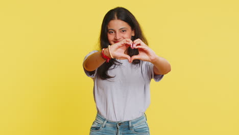 smiling pretty woman makes heart gesture demonstrates love sign expresses good feelings and sympathy