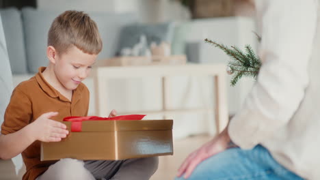 little boy opens christmas present with joy