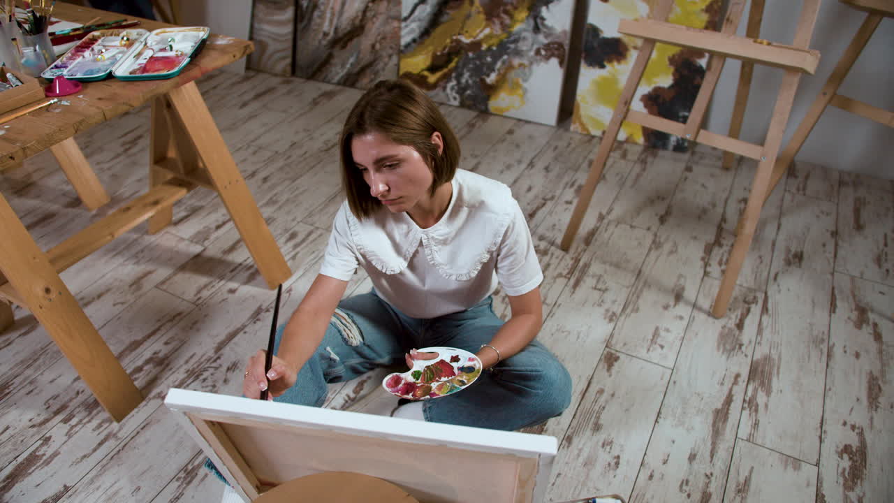 Young woman sitting on the floor with canvas
