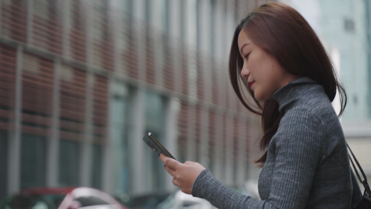 Asian businesswoman using phone walking