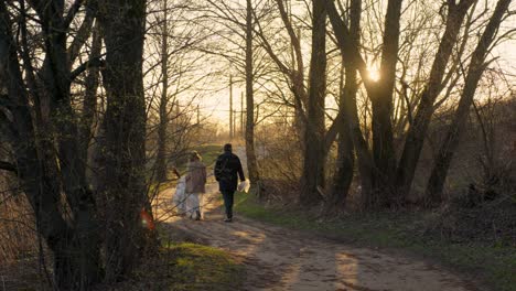 couple walking in nature during golden hour on their wedding day, soft and warm mood