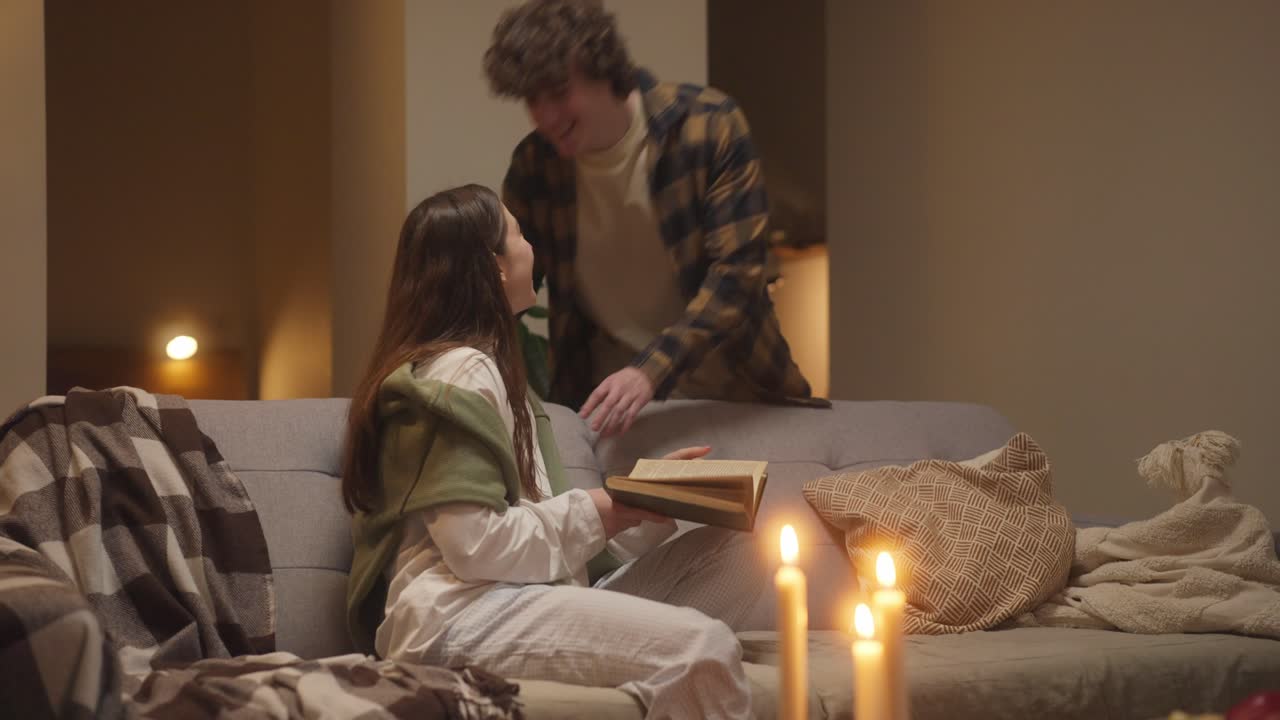 A couple enjoying a cozy evening reading by candlelight