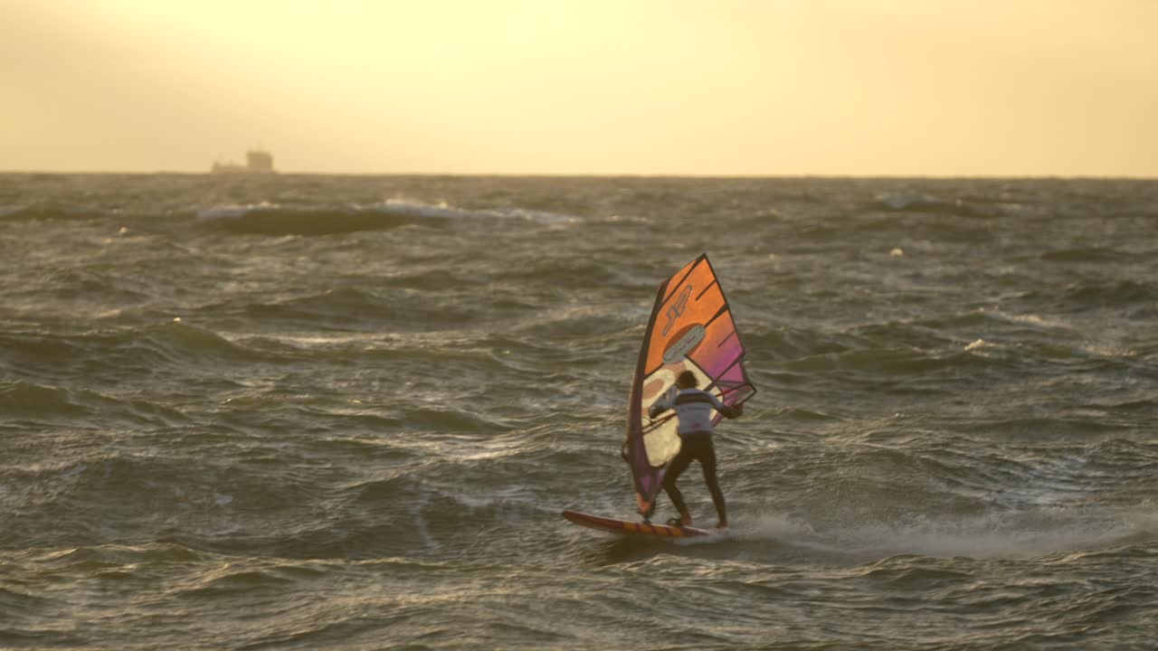 windsurfista de estilo libre saltando en la luz dorada del atardecer, capturado en 60fps, cámara lenta