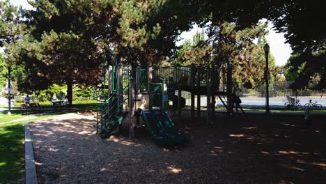 vuelo aéreo desde un parque restringido con varias regulaciones de covid-19 relacionadas con el cierre pandémico global en un parque infantil vacío con una cancha de tenis vallada activa en el fondo 1-2