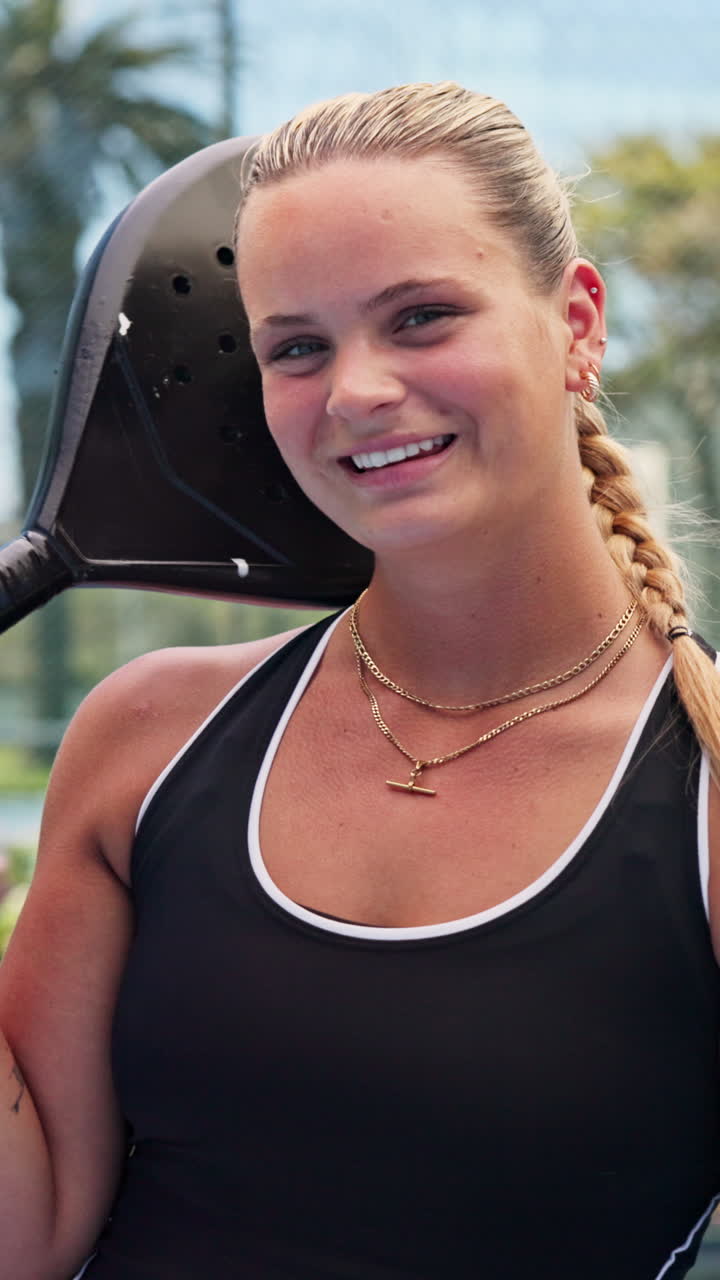 Giovane donna sorridente che tiene una racchetta da padel in campo
