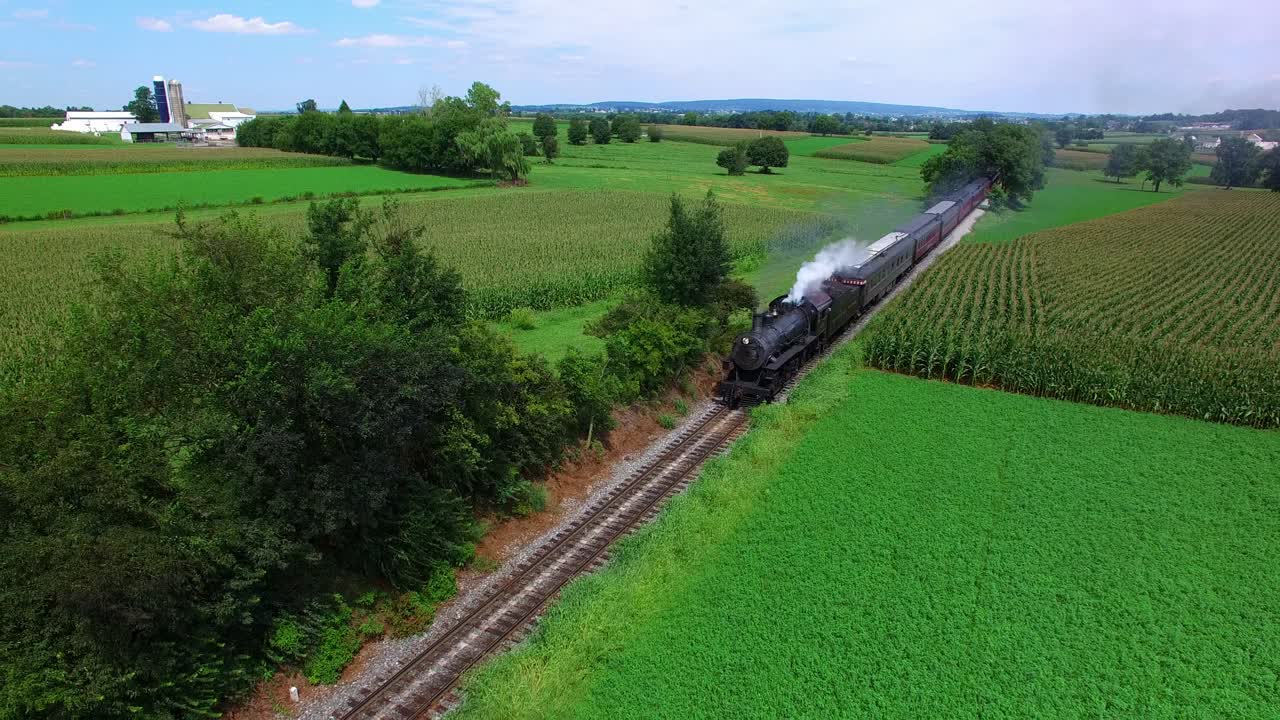 Steam Train Puffing along Amish FarmLand on a Sunny Summer Day as seen by a Drone