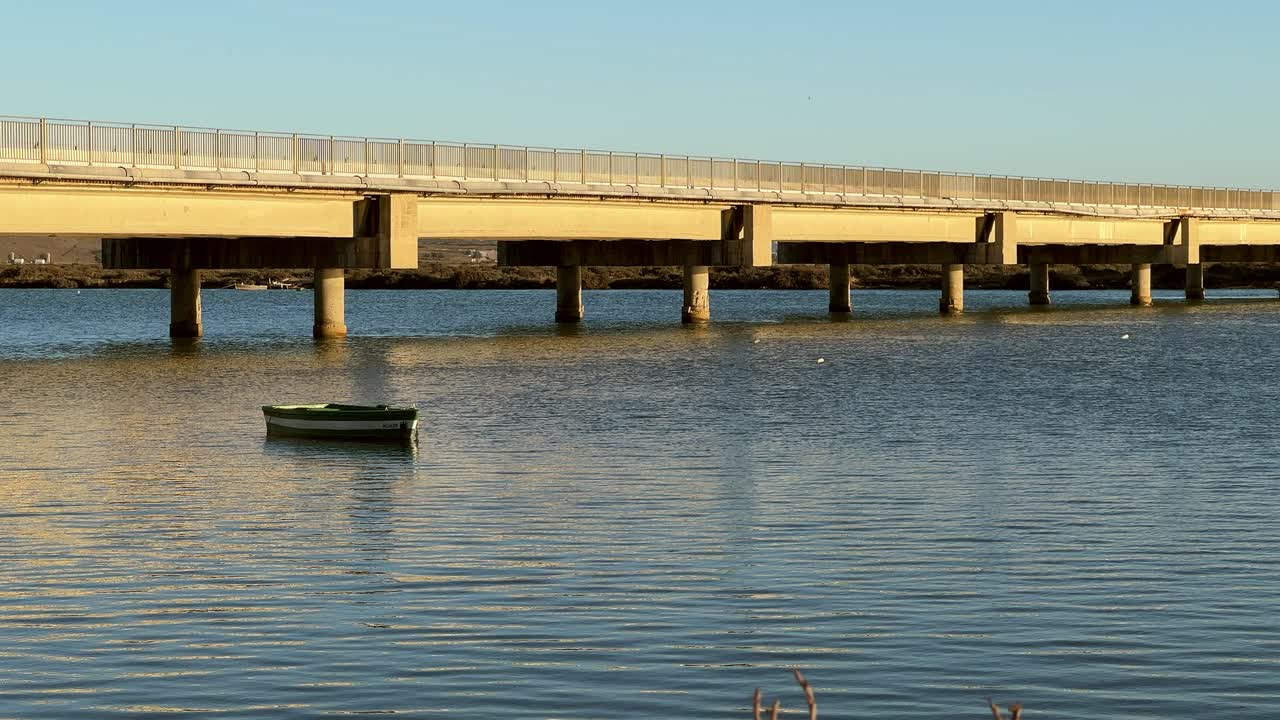 잔잔한 바다 위를 가로지르는 다리와 배 한 척이 있는 장면