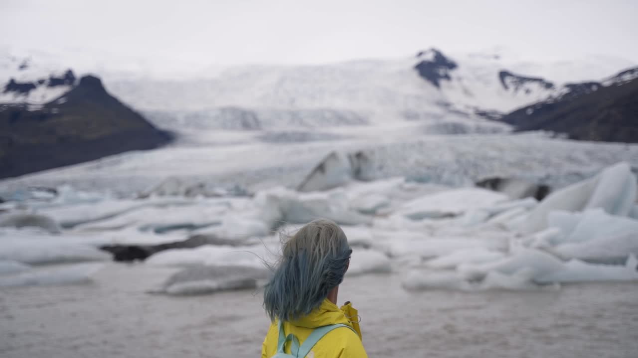 This was taken at a higher frame rate and has been converted to a slow motion video clip.  Lady looking at glaciers in Iceland.
