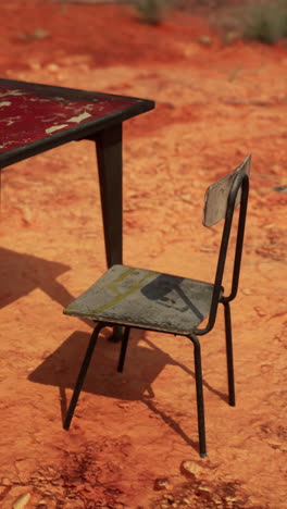 rusty metal chair and table in a red dirt field