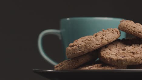 disparo de cerca de un plato de galletas de chocolate y taza de café girando