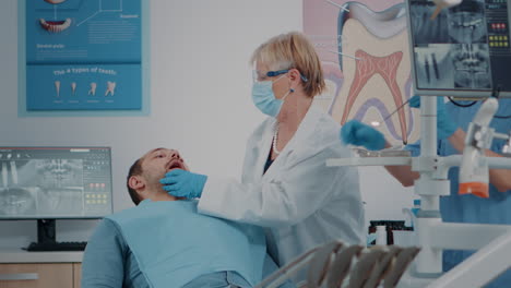 dentist with face mask using dental tools to examine denture