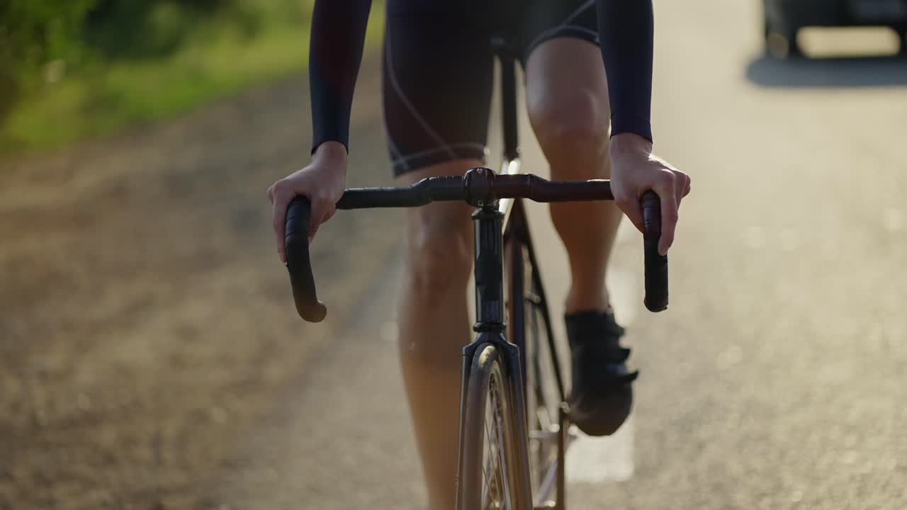 vista frontal recortada de un ciclista masculino montando en bicicleta a lo largo de la pista por la mañana, cámara lenta