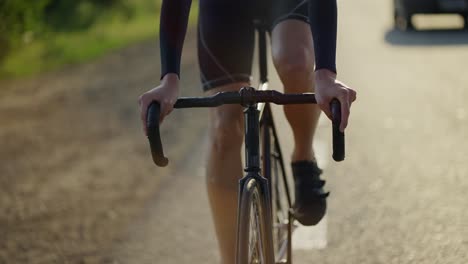 cropped front view of a male cyclist rides bicycle along track in the morning, slow motion