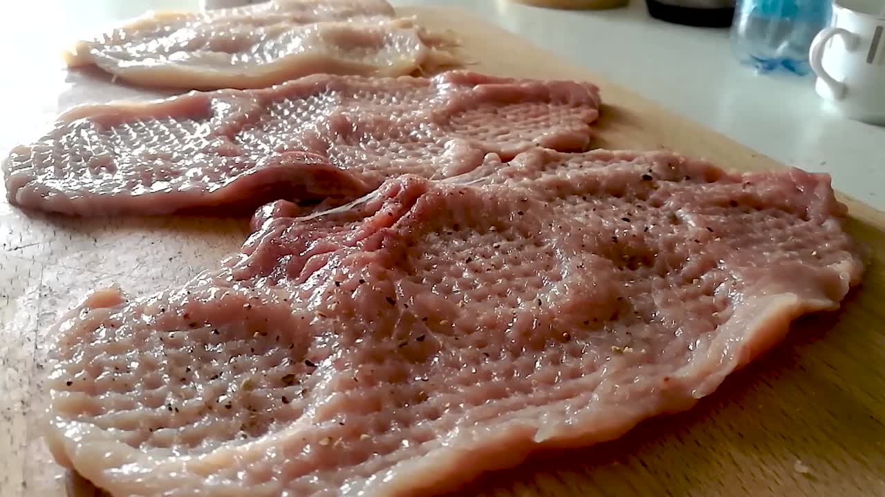 굵은 후추를 곁들인 도마에 얇게 썬 돼지고기 허리